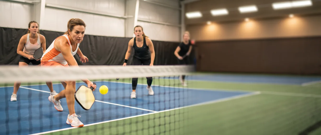 Adult league pickleball doubles player punching a volley at the net